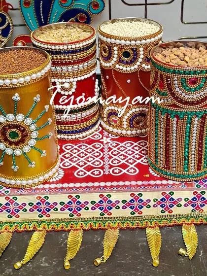 A set of traditional containers, meticulously decorated with beads and jewels, ready to be filled with auspicious items for a housewarming ceremony.