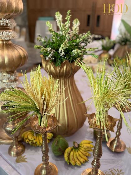 A beautiful arrangement for a traditional ceremony, featuring paddy stalks, bananas, and flowers in brass vessels, symbolizing harvest and prosperity.