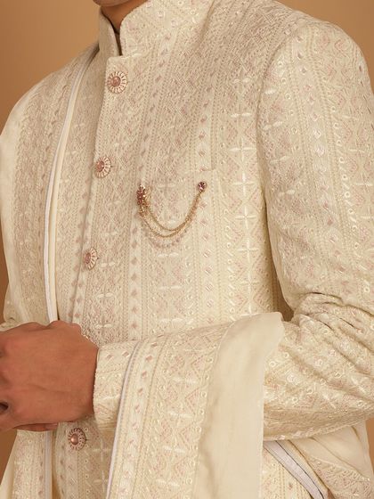 A detailed close-up of the intricate embroidery and elegant buttons on our ivory achkan. Every element is carefully chosen to contribute to a look of understated luxury.