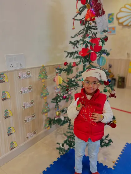 A student in a Santa hat poses by the tree, fully embracing the Christmas spirit.