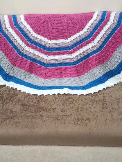 The semi-circle shawl spread out on a couch. This shows the full shape and the bold, graphic stripes.