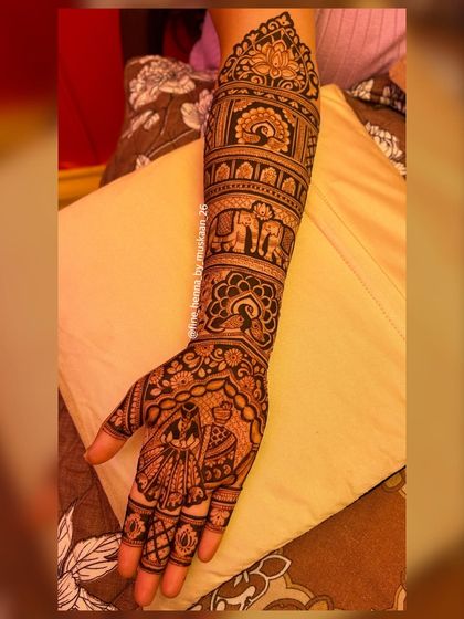 A single arm view of a classic bridal design. You can see the layers of patterns, from the dancing bride on the palm to the elephants and peacocks moving up the arm.