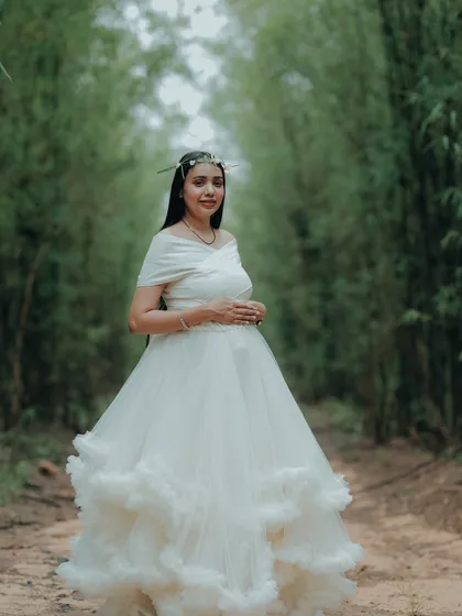 This white ruffled gown combined with a floral crown creates a beautiful bohemian look for a maternity shoot in the woods.