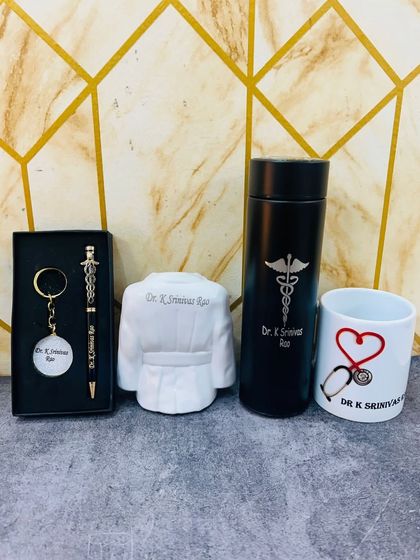 A complete gift combo for a doctor. This set includes a personalized temperature bottle, a pen and keychain set, a mug, and a unique pen stand shaped like a doctor's coat.