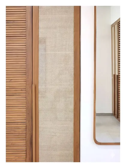 A detail of a wardrobe combining louvered wood and cane panels. This pairing of textures is not just for aesthetics; it provides ventilation while maintaining visual lightness, a principle I apply to make furniture both beautiful and practical.