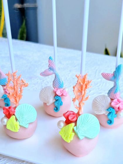 Intricately decorated cakepops for a mermaid theme, featuring fondant tails, corals, and shells.
