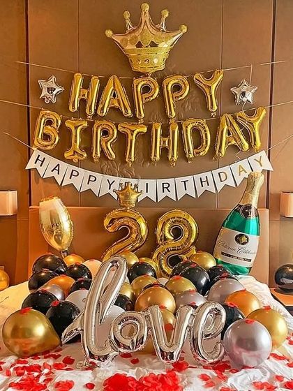 A celebratory birthday setup right on the bed. This arrangement includes gold and black balloons, 'Happy Birthday' and 'Love' foil balloons, and number balloons for the age, perfect for a hotel room surprise.