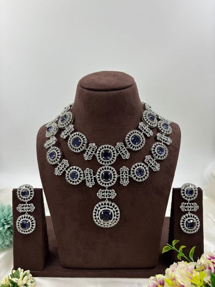 This bold, silver-plated AD set features large circular motifs. It's a statement piece available in sapphire blue, emerald green, ruby red, and all-white, perfect for customers who want to stand out.
