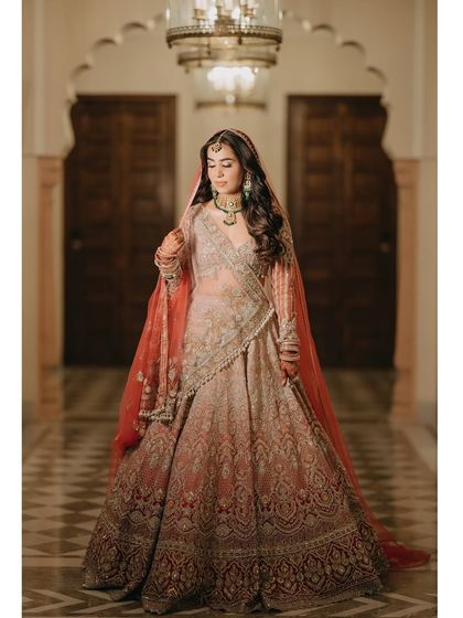 A full-length portrait of Chitranksha in her stunning bridal lehenga. The soft lighting and the elegant corridor of the Mementos by ITC Hotels in Jaipur provide a perfect backdrop for her regal look.