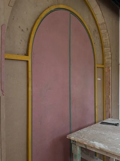 The making of our bespoke entrance door. This image shows the raw MDF and plywood structure, meticulously templated to create the perfect arched form that would later be wrapped in a custom-designed, embellished fabric skin.