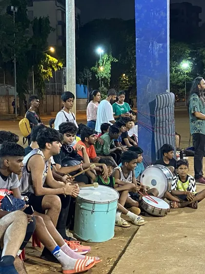 The audience and players watching the game, with drums ready to bring the noise and energy.