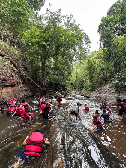 A group of campers enjoys the cool waters of a forest stream in Ulavi, a rewarding end to a challenging trek.