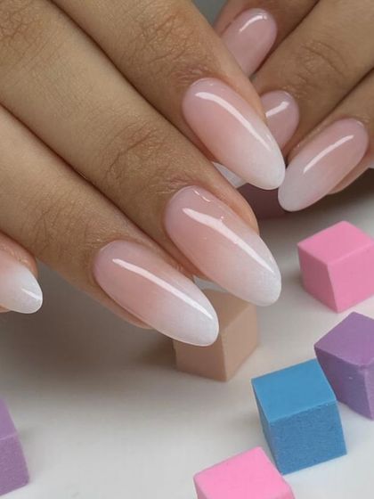 A flawless ombré manicure on almond-shaped extensions. The gradual transition from the nude base to the soft white tip is perfectly blended.