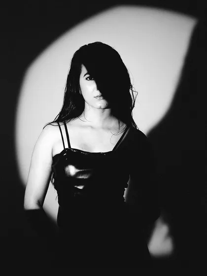 Black and white photography strips away everything but the essential. Here, I used a focused spotlight to play with shadow and light, creating a mysterious and captivating portrait that feels timeless.