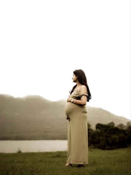 A stunning solo portrait of the mom-to-be standing by the lake, looking out at the mountains. The minimalist composition highlights her silhouette and the peacefulness of the moment.