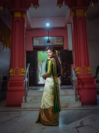 A beautiful portrait of a woman in a traditional South Indian saree at a temple. The shot from behind as she looks back creates a graceful and classic pose.
