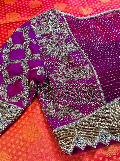 A truly royal creation for a special client. This magenta blouse is a showcase of heavy craftsmanship, featuring intricate zari and beadwork on a traditional bandhani base, with unique scalloped sleeve cuffs for a regal finish.