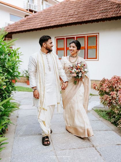Navitha and Orville taking a walk after their ceremony, hand in hand. The simple elegance of their traditional attire is beautifully complemented by the natural surroundings.