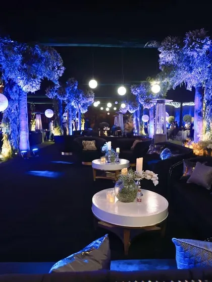 Another perspective of the expansive lounge, showing the deep blue velvet sofas and the enchanting glow from the illuminated trees and hanging lights.