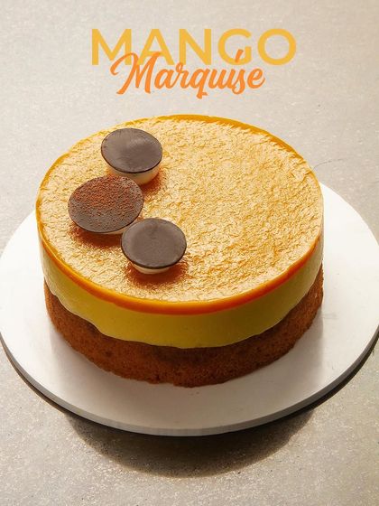 My Mango Marquise cake is a sophisticated dessert with a smooth mango mousse set on a light sponge base. It's elegantly finished with chocolate discs, offering a refined taste of the tropics.