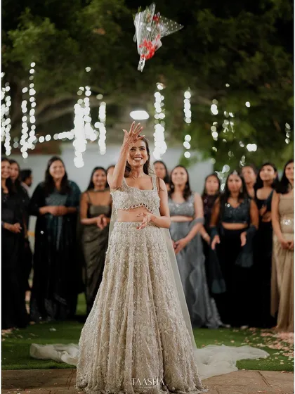 As the night comes alive with fairy lights, so do the celebrations. A bouquet toss on the lawn is a moment of shared joy and laughter, creating memories that will be cherished long after the day is done.