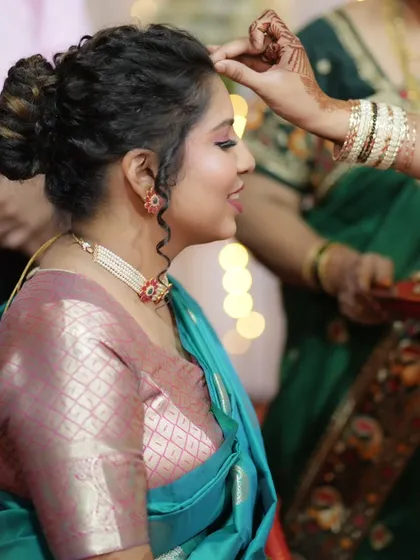 A candid moment from the engagement pooja, showing the bride's elegant side profile and intricate braided bun hairstyle.