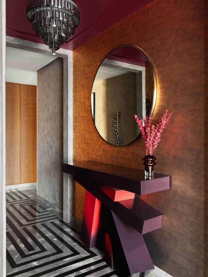 A dramatic corridor with bold geometric flooring and a sculptural console table showcases the home's fearless use of color and form.