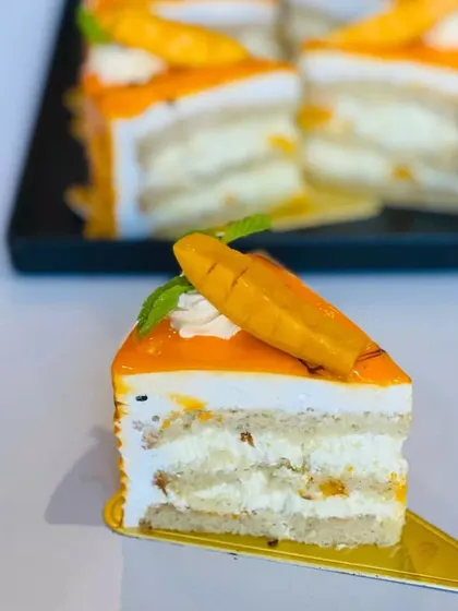A slice of our light and airy Mango Pastry. It's layered with fresh mango pieces and delicate cream, making it a refreshing and delicious seasonal treat.