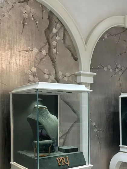 The interplay of our custom wallpaper and the architectural details of the store. The arched frames beautifully highlight the serene, hand-painted design, creating a truly bespoke interior.