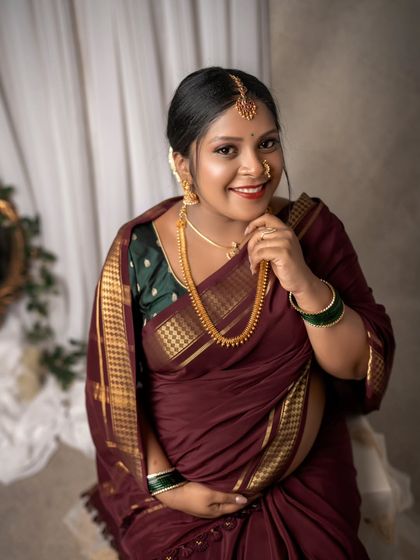 This close-up portrait highlights the joyful smile of the mom-to-be. Her traditional attire, complete with a maang tikka and nose ring, beautifully frames her happy expression.