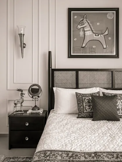 A bedroom from our 'Heritage Hue' project, featuring a classic bed with a cane headboard and traditional Indian art, presented in a timeless black and white finish.