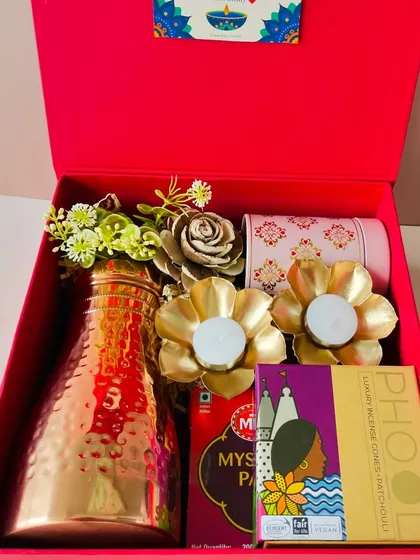 This vibrant red magnetic box for Diwali features a hammered copper bottle, floral T-light holders, and luxury incense sticks. It's a gift that combines utility and tradition.