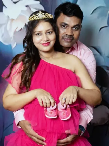 A close-up couple shot from the same family maternity session, focusing on the connection and the tiny shoes symbolizing the baby on the way.