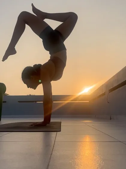 A silhouette of a handstand against the setting sun. This image captures the power and beauty that comes from dedicated practice and learning to see the world from a different perspective.