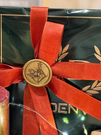 The final touch of elegance: a custom wax seal on a dark green gift box, part of our Valentine's hamper for him.