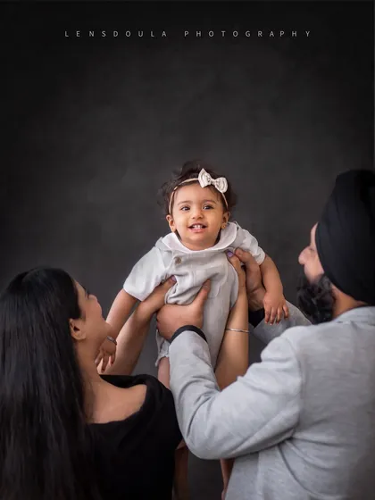 A beautiful family portrait where the focus is all on the baby's happy face. Lifting the child up creates a dynamic and joyful composition.