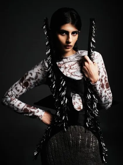 A close-up of the edgy, high-fashion look, focusing on the intense, dark eye makeup. The hair is pulled back tightly to keep all the attention on the model's expression and the unique garment.