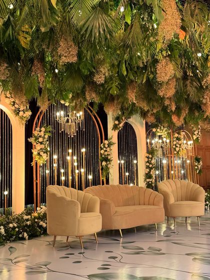A closer look at the greenery-draped stage, showing the elegant beige seating and the warm glow of the lights.