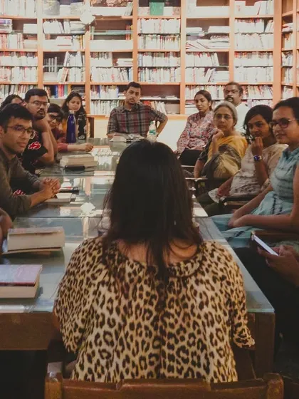 A candid shot from one of our book club meetings. A group of readers engaged in a lively discussion, surrounded by bookshelves. This is community in action.