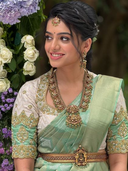 A classic portrait of the bride, showcasing her beautiful pastel green saree and antique gold jewelry.