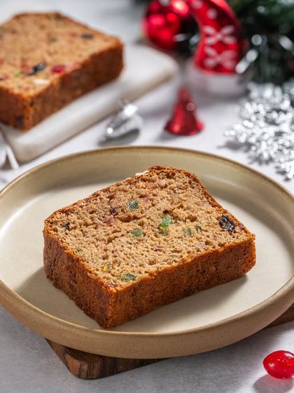 A slice of classic fruit cake, showing the colorful candied fruits inside, styled for a Christmas menu.