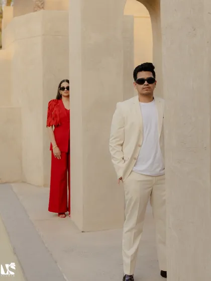 A stylish, modern portrait set against the minimalist architecture of the Dubai desert. The bold red and clean white outfits create a stunning contrast, showcasing how we blend high fashion with intimate storytelling.