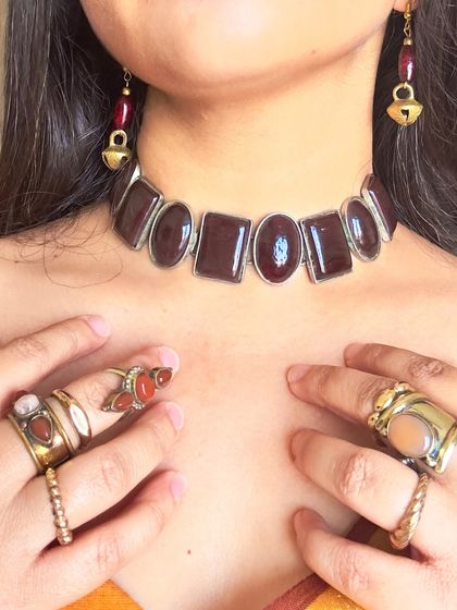 A close-up on the beautiful brass and stone jewellery. The dark red stones in the choker and earrings perfectly pick up the subtle brown tones in the saree's border.