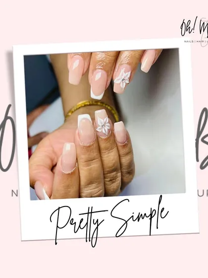 Pretty and simple elegance. This design combines a classic French manicure with a 3D white floral accent on the ring finger, adding a touch of sophistication.