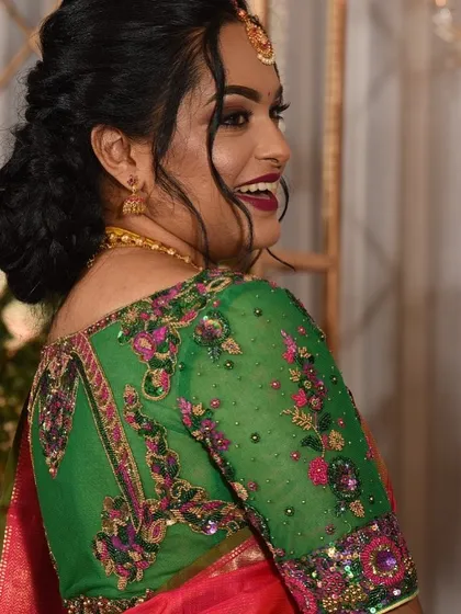 This client is radiant in a custom hand-embroidered blouse. The bright green sheer fabric is covered in a beautiful floral design using pink and gold thread, creating a stunning contrast.