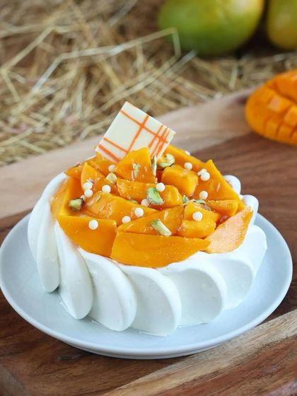 This mini mango cake is a personal indulgence. It's topped with a generous amount of fresh mango chunks and pistachio slivers, offering a burst of flavor in every bite.