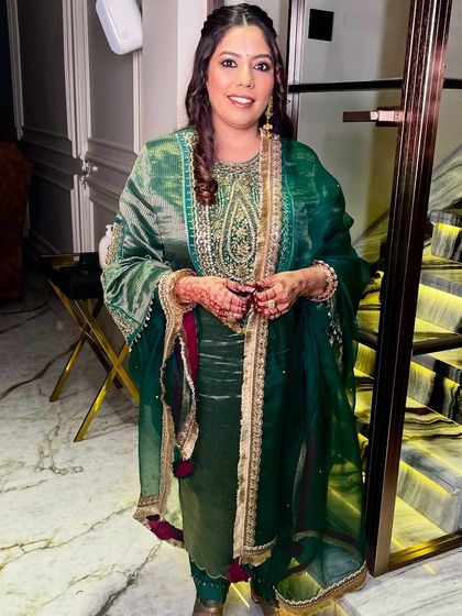 The full look, showcasing the elegant green outfit and the soft, glowing makeup.