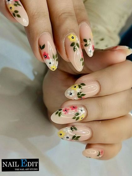 This design features beautiful, hand-painted floral vines on a sheer nude base. The delicate flowers in red, yellow, and white create a fresh, garden-inspired look on long oval nails.