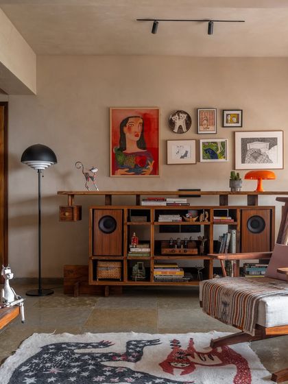 The living room was planned around our clients' vibrant collection of art and furniture. The custom-built media unit, crafted from teak, provides dedicated spaces for their speakers, books, and cherished artifacts.