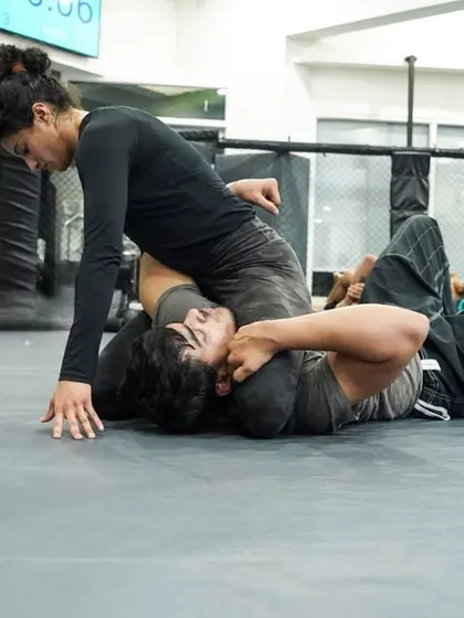 A female practitioner maintains a strong mount position, demonstrating excellent control and pressure from the top. This is a dominant position in any grappling scenario.